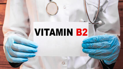 The doctor's blue - gloved hands show the word VITAMIN B2 - . a gloved hand on a white background....