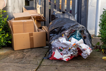 Christmas household waste consisting of boxes and wrapping paper at a trash can