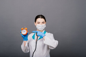 Smiling doctor woman pointing on clock, time to vaccine