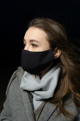 girl in a medical mask with a scarf on a black background