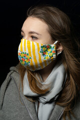 girl in a medical mask with a scarf on a black background