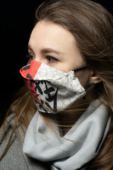 girl in a medical mask with a scarf on a black background