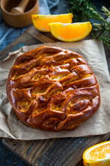 Orange pie on the wooden board with orange slices and wooden bowel on the side.