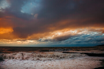 Abstract and colorful storm clouds. Sea sunset. A storm at sea. The waves hit the shore.