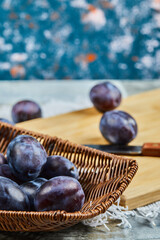 Garden plums in a basket on a table with knife