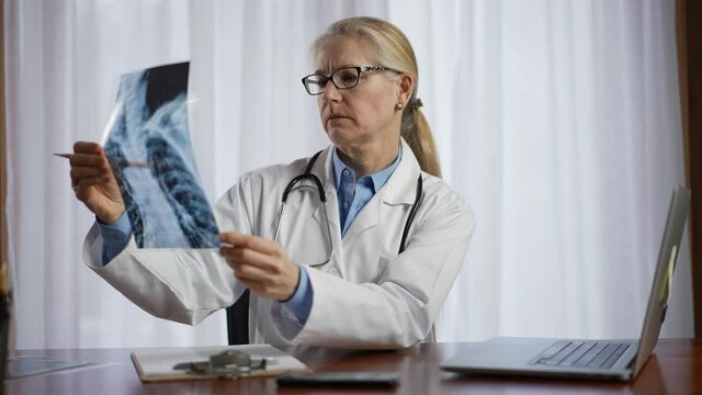 Doctor is looks at X-ray image of patient. Slow motion concept of doctor for personal healthcare in office.