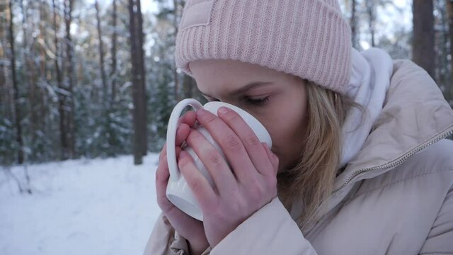 Female drink tea from cup in winter forest, slow moton.