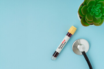 Stethoscope and blood sample vacuum tube on blue background. Corona virus concept with a copy space.
