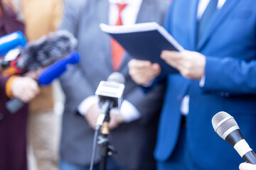 News conference, journalists with microphones interviewing politician or business person during...