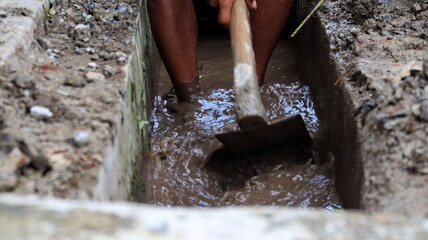 Selective focus image, workers clearing sewers from clogged trash