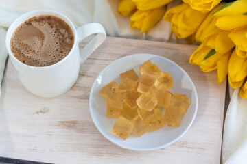 A bouquet of fresh yellow tulips and breakfast with coffee and homemade marmalade. Breakfast in bed. Spring flowers. The concept of spring and holiday, March 8, International Women's Day, birthday. 