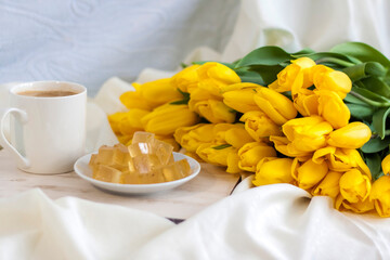 A bouquet of fresh yellow tulips and breakfast with coffee and homemade marmalade. Breakfast in bed. Spring flowers. The concept of spring and holiday, March 8, International Women's Day,