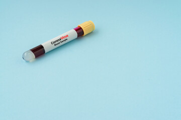 Blood sample vacuum tube on blue background with a copy space. Corona virus concept. Flat lay.