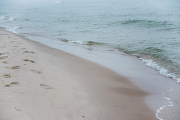 Fale morskie plaża we mgle ślady na piasku © Monika
