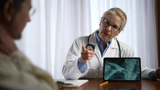 Doctor is shows X-ray images to patient on tablet pc computer. Slow motion concept of doctor discuss personal healthcare.