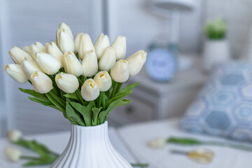 Tulips flowers in white vase on the living room coffee table. Composing bouquet. Still life