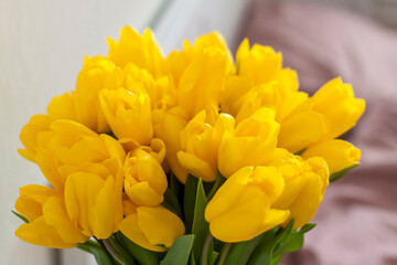 Obraz premium On the bed is a bouquet of yellow tulips. Bouquet of fresh tulips close-up. Spring flowers in the bedroom interior. The concept of spring or holiday, March 8, International Women's Day