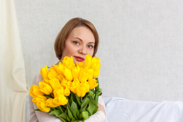 Portrait of a young beautiful girl. A girl and a large bouquet of fresh yellow tulips. The concept of spring and holiday, March 8, International Women's Day,
