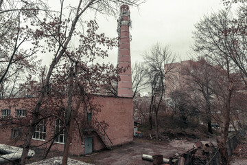 An old abandoned boiler room with a tall brick steam pipe