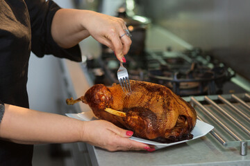 thanksgiving, christmas, baked goose for a festive dinner with a golden brown crust on a white porcelain plate in female hands.