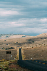 Winding asphalt road in dry hilly grasslands of Utah.