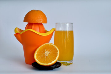 A glass of juice, a juicer and an orange.