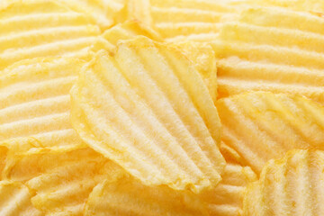 Potato chips pattern. Yellow corrugated salted potato chips as food background. Chips texture, studio photo, close up