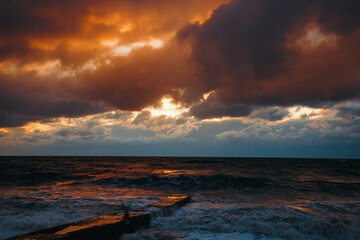 Naklejka na ściany i meble Abstract and colorful storm clouds. Sea sunset. A storm at sea. The waves hit the shore.