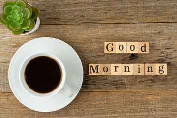 A cup of coffee with a text Good Morning on a shabby wooden board background. Flat lay.
