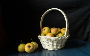 Ripe pears in basket on black background with reflection