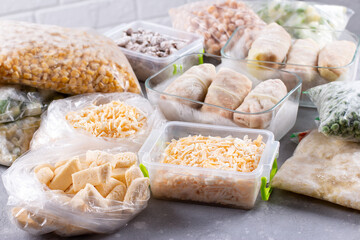 Plastic bags and containers with different frozen products, vegetables and meat