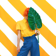 Unrecognizable Model holding palm leaf and wearing vintage look on trendy striped yellow...