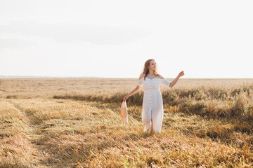 Girl with long curly hair poses in a wheat field