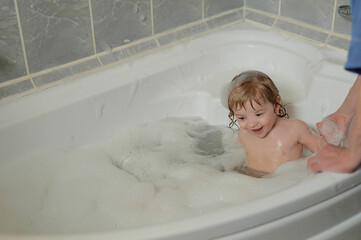 Grandmother playing with smiling baby in bubble bath