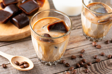 Ice coffee with milk being poured in a glass on a table