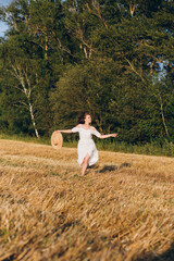 Naklejka na ściany i meble Girl with long curly hair poses in a wheat field