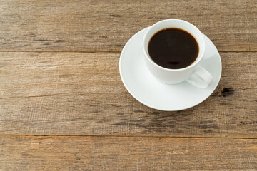 A cup of coffee on a shabby wooden board background.