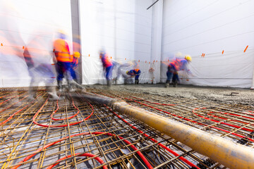 Workers do concrete screed on floor with heating in a new warehouse building