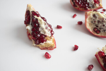isolated pomegranate fruit slices with seeds close-up on a white background, red color