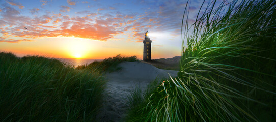 Lighthouses with beacon on coast in windy stormy sea and beach with dunes and grass