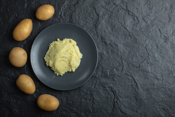 Fresh potatoes and mashed potatoes. Top view. black background