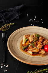 chicken stew with vegetables and pineapples on a black textured background