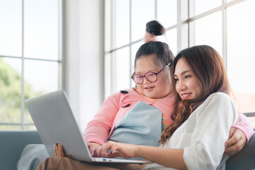 Happy asian family with their daughter down syndrome child sitting on sofa have fun using laptop watch a movie for education , Enjoy relax timing together, Activity happy family lifestyle concept.