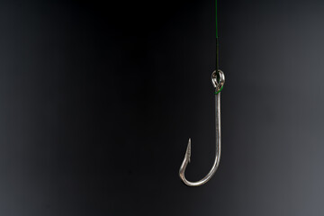 Fishing hook on a black background. trap, catch on, risk. Business concept idea