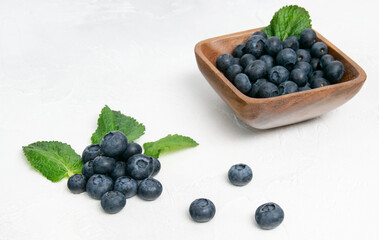 Blueberry berries with mint leaves are on the table in a wooden mold