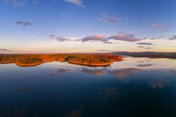 Drone aerial view of a lake reservoir of a dam with perfect reflection on the water of the sunset in Sabugal, Portugal © Luis