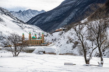 a mosque with green domes at the bottom of a gorge in the mountains of Ingushetia 