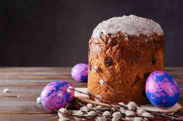 pink  eggs, willow twigs, Easter cake with icing and raisins on a dark wooden background