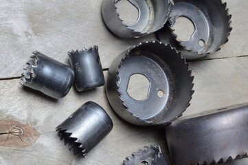 a set of old crowns for drilling a tree lies on a plank, wooden background. close-up.