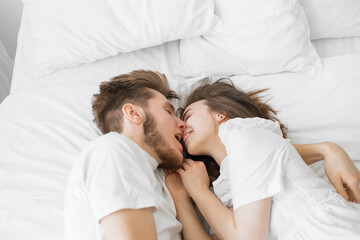 guy and girl lie on a white bed. Flat lay top-down